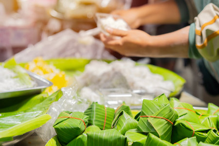 Thai street food seller at the night market in Chiang Mai, Thailand. Selective focus on a local snacks wrapped in banana leavesの写真素材