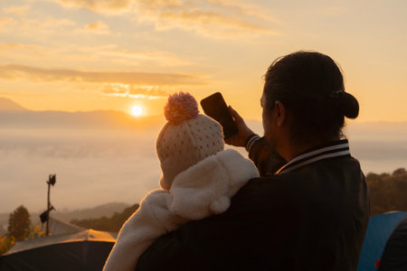 Happy father holding little baby daughter and making a selfie at high mountain.の写真素材