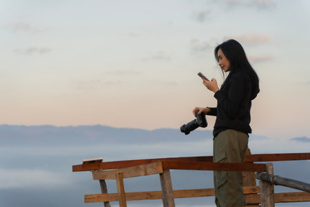 Young tourist woman using phone and taking a photograph of mountain in Chiang Mai province of Thailand in the morning.の写真素材
