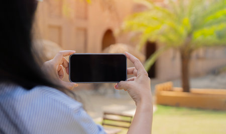 Close up hands of woman holding mobile phone in hands and taking photo for share with friends on social mediaの写真素材