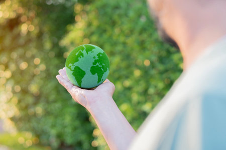 Cropped view from the shoulder of earth in man hand at outdoor. Save of earth. World environment day and sustainable environment conceptの写真素材