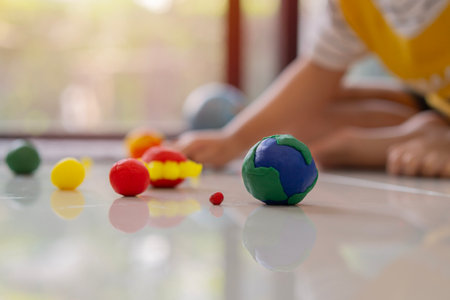 A male little child is playing with play dough and mold it into solar system model toy planets at home. Selective focus on earth.の写真素材