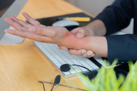 Business man, hands and wrist injury with computer for pain, discomfort or carpal tunnel syndrome at office. Side view close-up.の写真素材