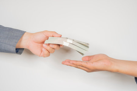 Businessman giving or paying stack of dollars banknote to a man over white background. Financial concept.の写真素材