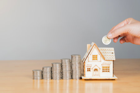 Saving money concept. House Model and Coins Stacks on wooden table. Save and investment money for...