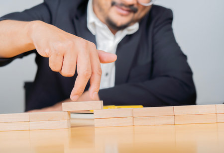 Cropped image of businesspeople solving problems by building bridges with wooden blocks, walking across risk between wood blocks.の写真素材