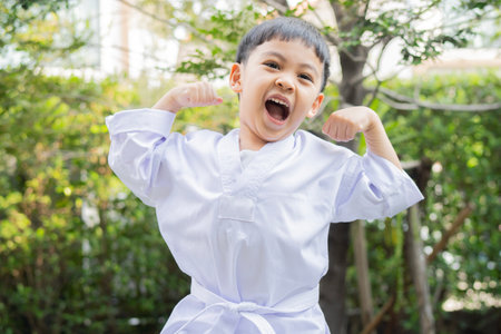 Happy Asian little boy practicing karate outdoor. Sport karate kids. Little boy wearing kimono doing karate in park.の写真素材