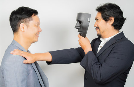 A business man with a black mask covering the insincerity of doing business together.の写真素材