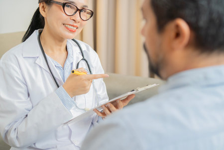 Medicine, healthcare and people concept. Happy female doctor with clipboard talking to mature man patient at hospitalの写真素材