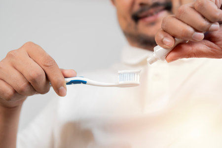 Mature man putting on toothpaste to brush his teeth in the bathroom. Selective focus.の写真素材