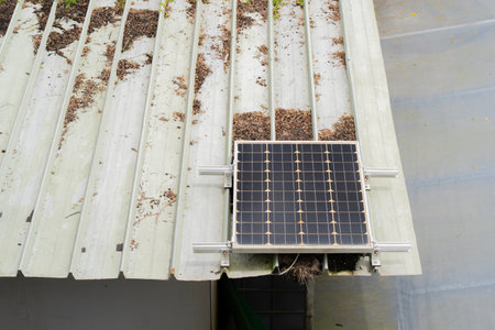 Mini solar panel installed on the roof of an old storage building with tree branches. Concept for using natural power from the sunlight at home in daily life.の写真素材