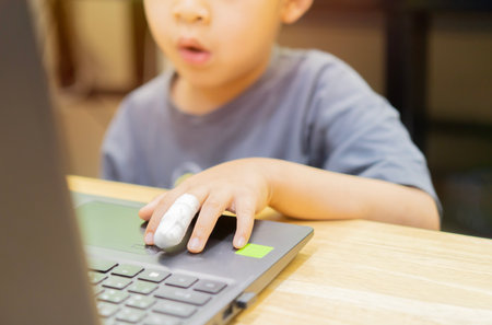 Little boy injured finger and bandaged use a laptop computer mockup for app, game or web site design...