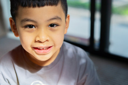 Adorable Asian little boy smiling into camera. Portrait of a boy at home. Happy child portrait with...