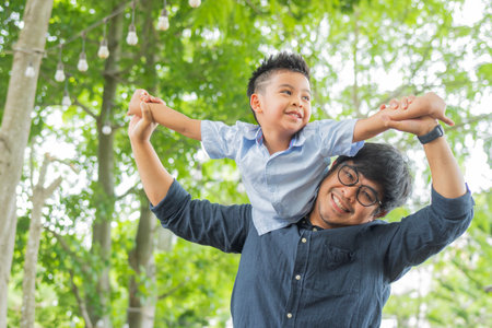 Portrait of dad playing with his son on nature background. Father and little son are playing and having fun outdoors. Fathers day, holiday, happy family lifestyle concept.の写真素材