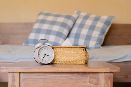 White vintage alarm clock with woven tissue box on wooden table, time symbolism