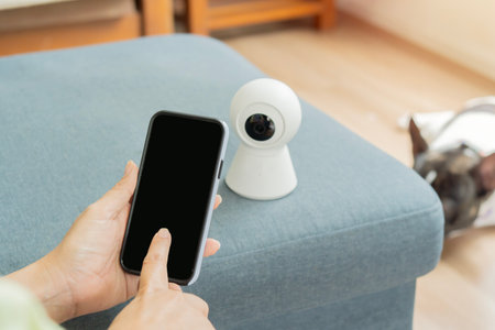 Woman hand presses the phone the connect the surveillance camera application at home with her pet....