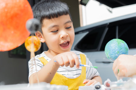 Asian preschool boy with mother and interacting doing painting the earth learning about the solar system outdoor at home, Homeschooling and distance learning.の写真素材