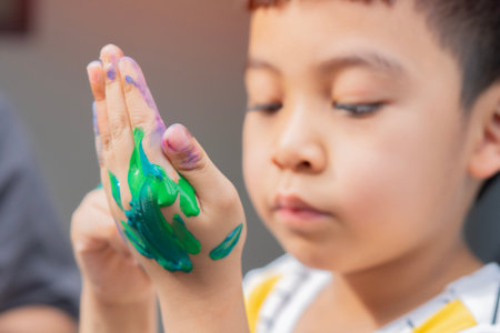 Little boy Intending to painting on his hands while playing with colors, concept of art and mess and creativity. Selective focus.の写真素材