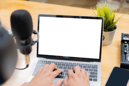 A man host streaming his audio podcast using microphone and laptop with isolate screen at his small...