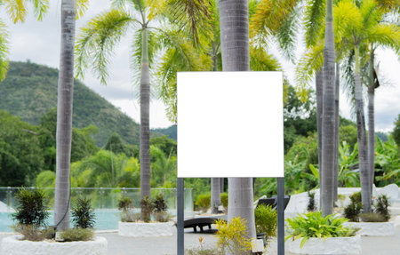 A white blank sign on one metal stands in the swimming pool area in a resort amidst mountains in the countryside. Copy space.の写真素材
