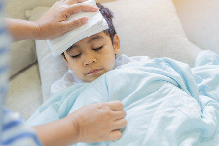 Sick Asian little child sleeping on bed, have cool towel for reduce high fever.  Selective focus, Healthy and infection conceptの写真素材