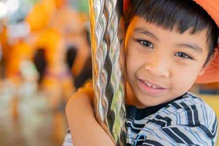 Close-up portrait image of adorable little Asian boyl in striped t-shirt at amusement park having a ride on the merry-go-round. Copy space.の写真素材