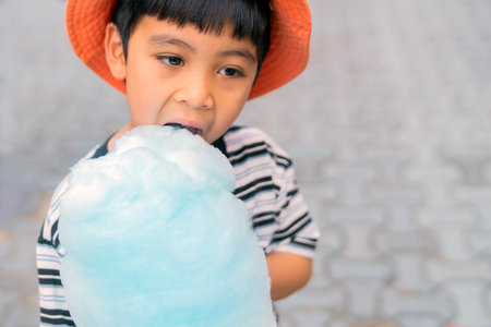 Happy child eating cotton candy and enjoying the holidays and summer at the carousel. Copy space.の写真素材