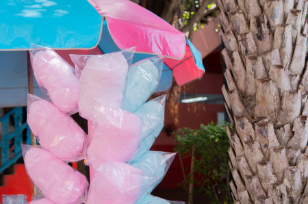 Cotton candy. Candy floss for sale at a wooden kiosk on the street. Sale of sweet food. Pink and blue cotton candy in plastic bags at street market stall.の写真素材