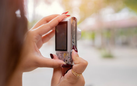 Young Asian woman traveler using digital compact camera, enjoying street cultural local place. Rear...