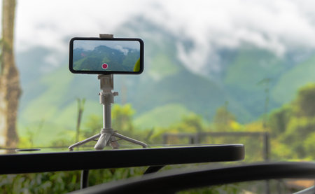 The phone on a tripod horizontal stands at morning fog on a green mountain.  A beautiful high mountain landscape has a place for an inscription close-up on the phoneの写真素材