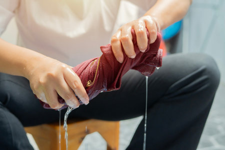 A woman wrings out a hand-washed dress, close-up view. Laundry, washing by hands. Washing at home, housekeeping and housework.の写真素材