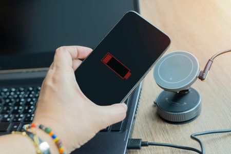 Woman charging mobile phone with wireless fast charger pad on desktop. Modern technology, portable...