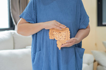 Senior woman holding large intestine organ made form paper in livingroom at home. Concept of healthy...