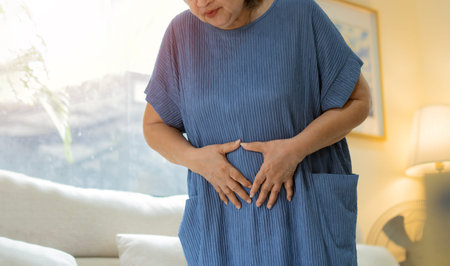 Older Asian woman is having stomach ache pain. Senior or mature people suffering from digestion...
