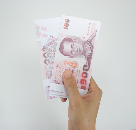 Giving money, money in hand outstretched in front of a white background.