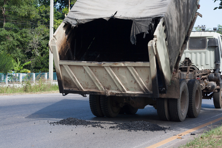 Repair of roads paved, the rear truck pouring asphalt on the road.の写真素材