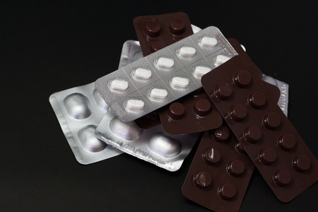 Concept medicines has expired. Pills or capsules on a black background, closeup.