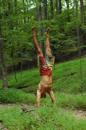 Head stand  in the woods by a young manの写真素材