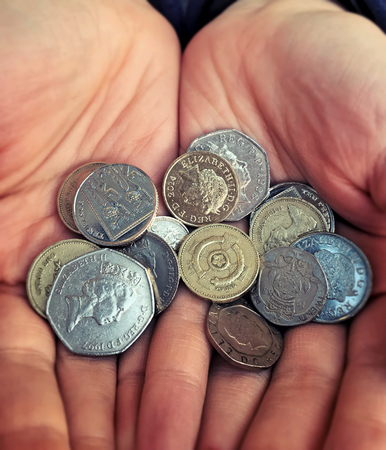 Hands with British pound coinsの写真素材