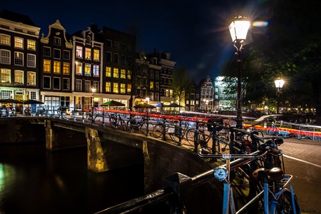Night view with bridge, bicycles and water reflection in Amsterdam city, Netherlandsの写真素材