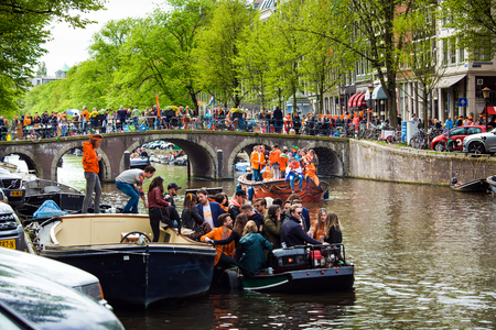 Amsterdam, Netherlands - April, 2018: Boats on Amsterdam canals with people celebrate King's day in Netherlandsのeditorial素材