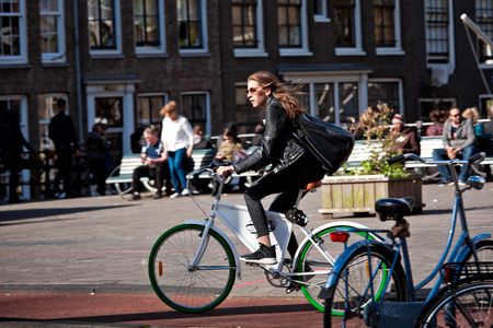 Amsterdam, Netherlands - April, 2018: Cyclist girl on Amsterdam street in Netherlandsのeditorial素材