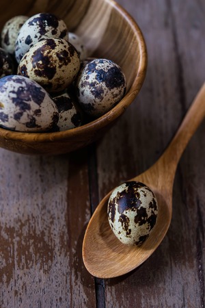 Quail eggs in wooden apoon and bowl on wood backgroundsの写真素材