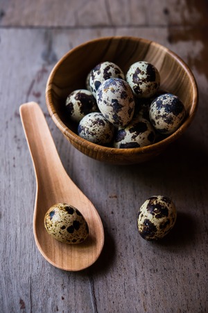 Quail eggs in wooden bowl on wood backgroundsの写真素材