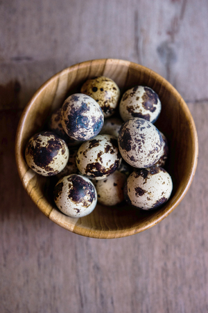 Quail eggs in wooden bowl on wood backgroundsの写真素材