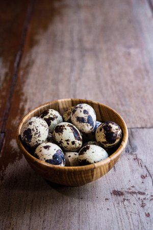 Quail eggs in wooden bowl on wood backgroundsの写真素材