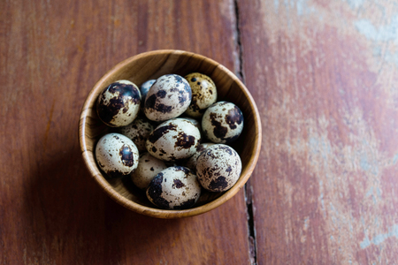Quail eggs in wooden bowl on wood backgroundsの写真素材