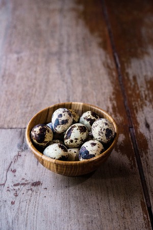 Quail eggs in wooden bowl on wood backgroundsの写真素材