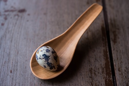 Quail eggs in wooden spoons on wood backgroundsの写真素材