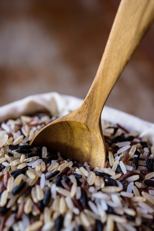 Rice in sack and wooden spoonsの写真素材